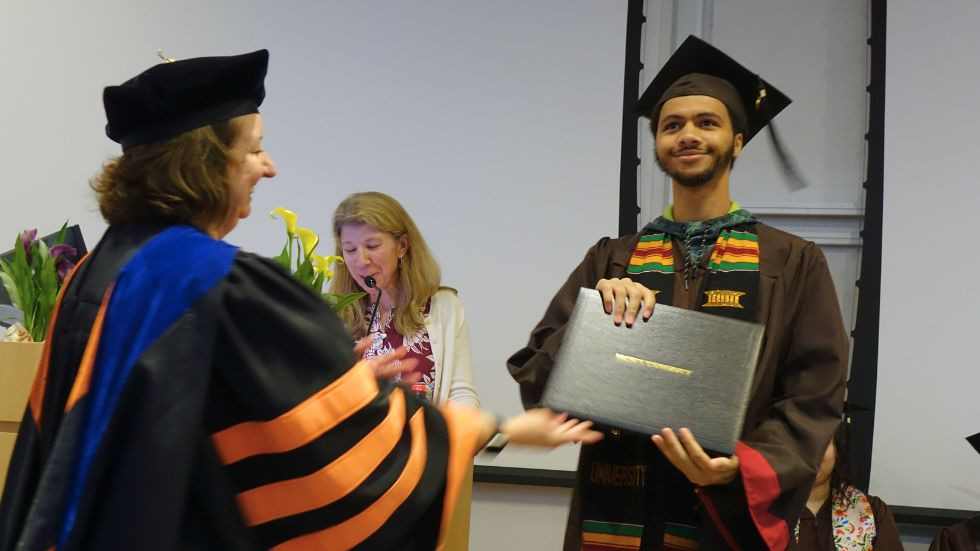 a student proudly receives his degree from the chair 