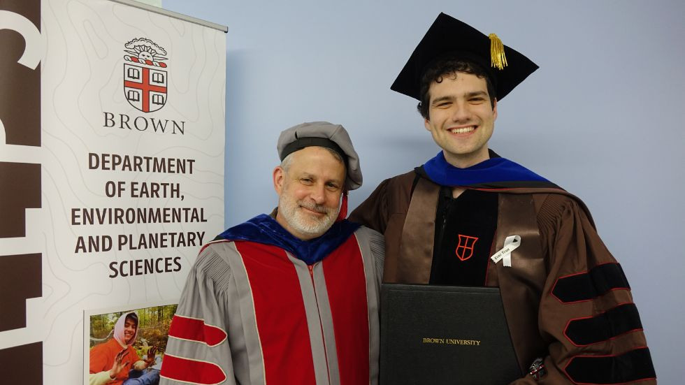 a professor and grad smile beside the DEEPS banner 