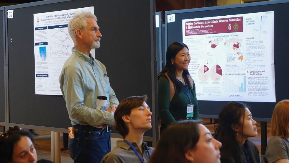 a professor and student stand at the back of the audience at DEEPS Dive