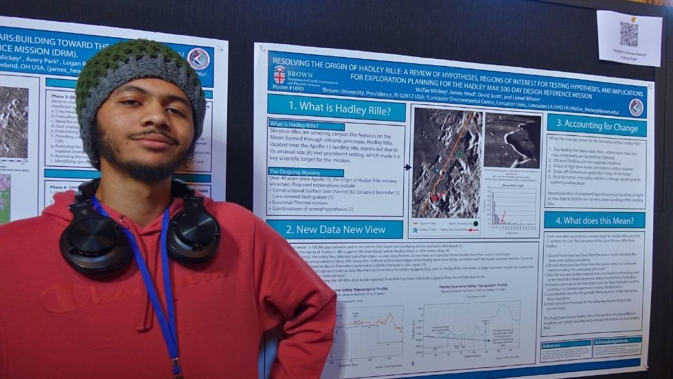 a student poses beside his research poster 
