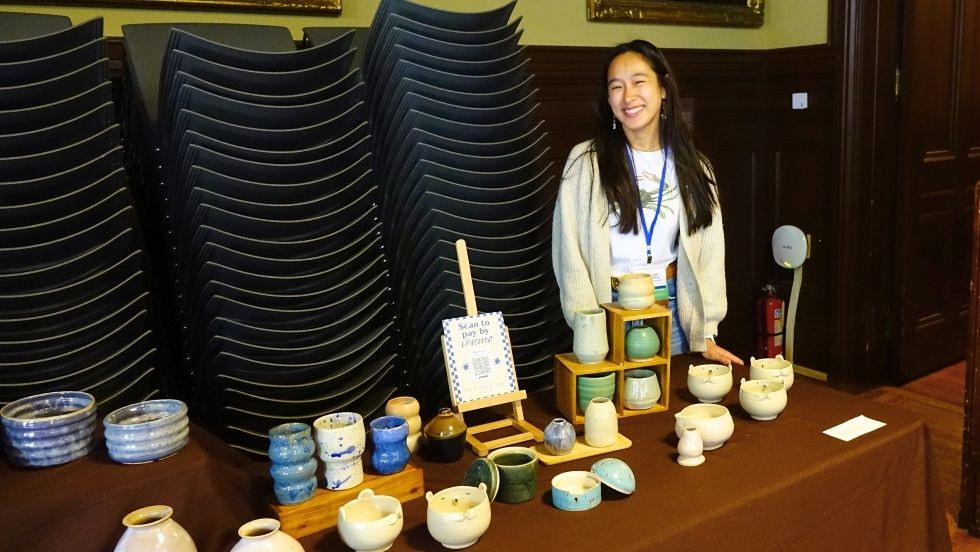 a student stands in front of her table of pottery 