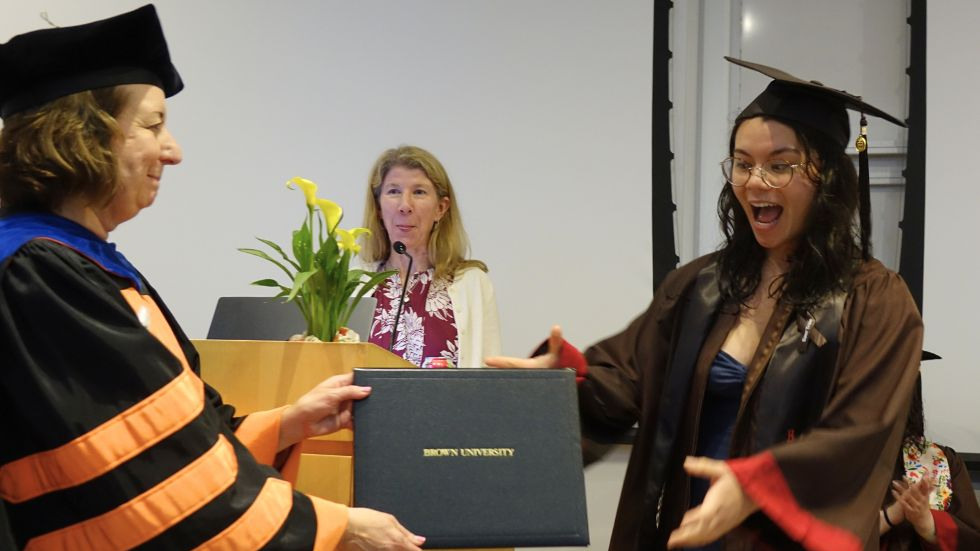 an undergrad smiles wide while receiving her degree from the chair 