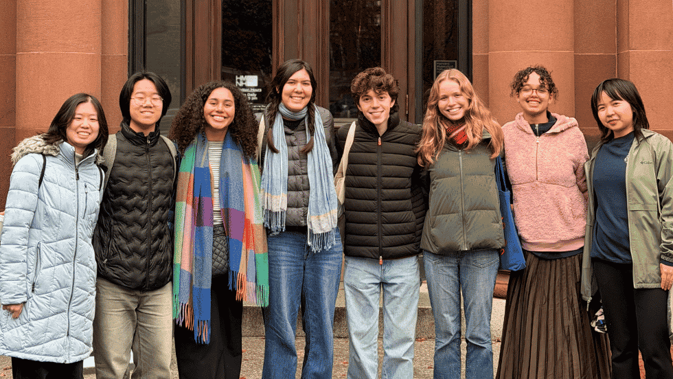 8 undergrads smile for a group photo together outside the Harvard Museum of Natural History