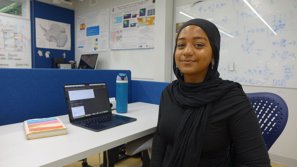 Maysha Chowdhury smiling beside her laptop 
