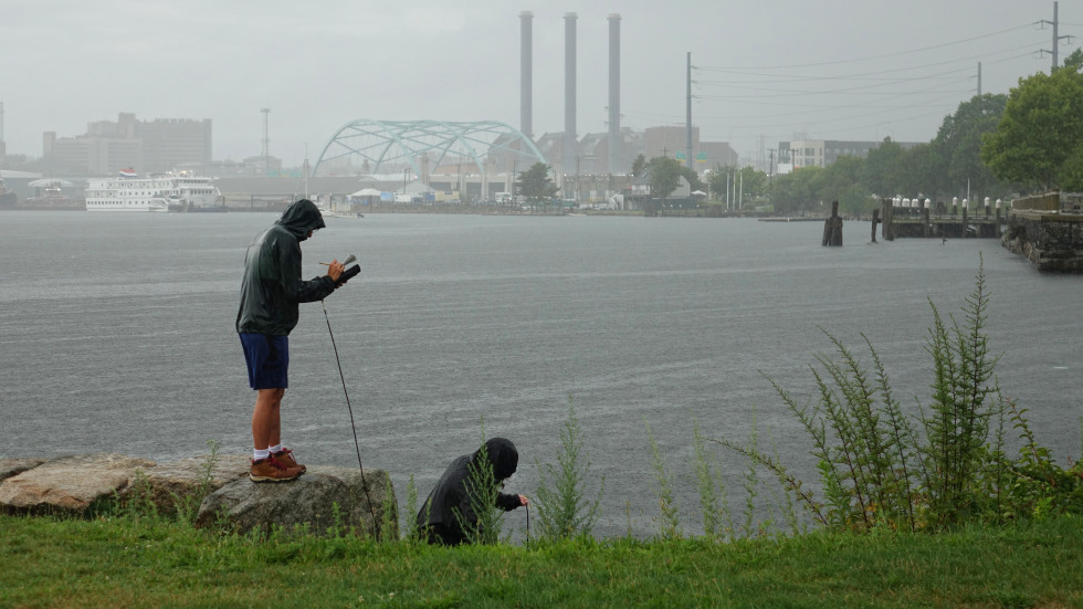 two students taking water samples from India point park in the rain