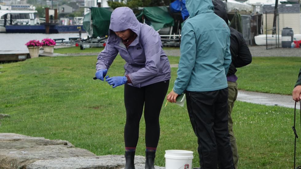 students working together to bottle water samples in the rain