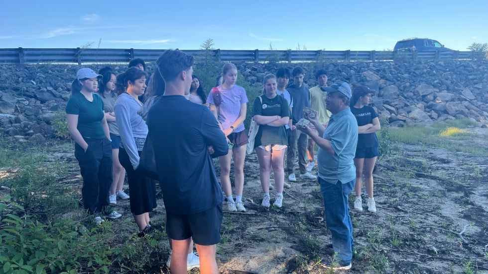 students circle around Professor Huang to review sediment samples