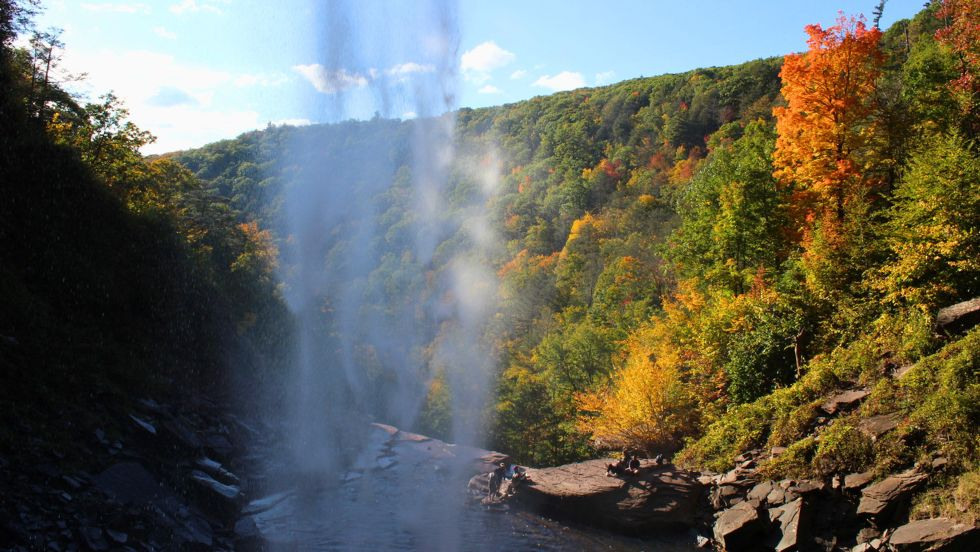 a view from behind the waterfall of students sitting near the water's edge