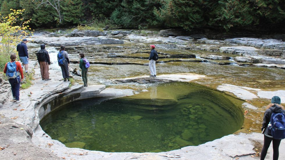 students walking along a rocky creek bed inspecting unique stone formations