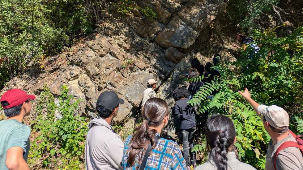 Professor Hodgin pointing out features in a rockface to a group of students 