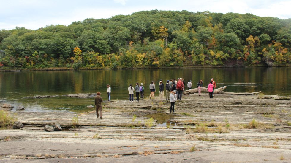 students gather in the distance along a rocky shoreline 