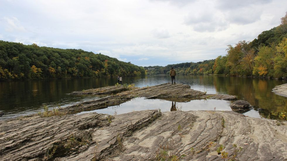 students looking out over the water from the rocky shoreline 